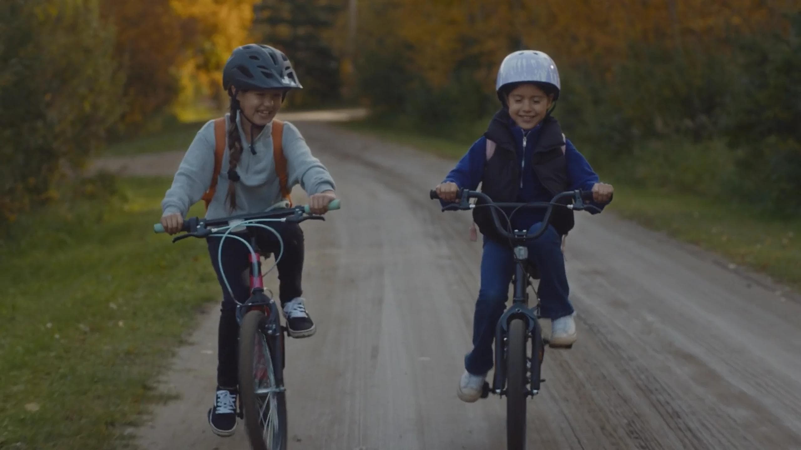 two children riding their bikes on a dirt road